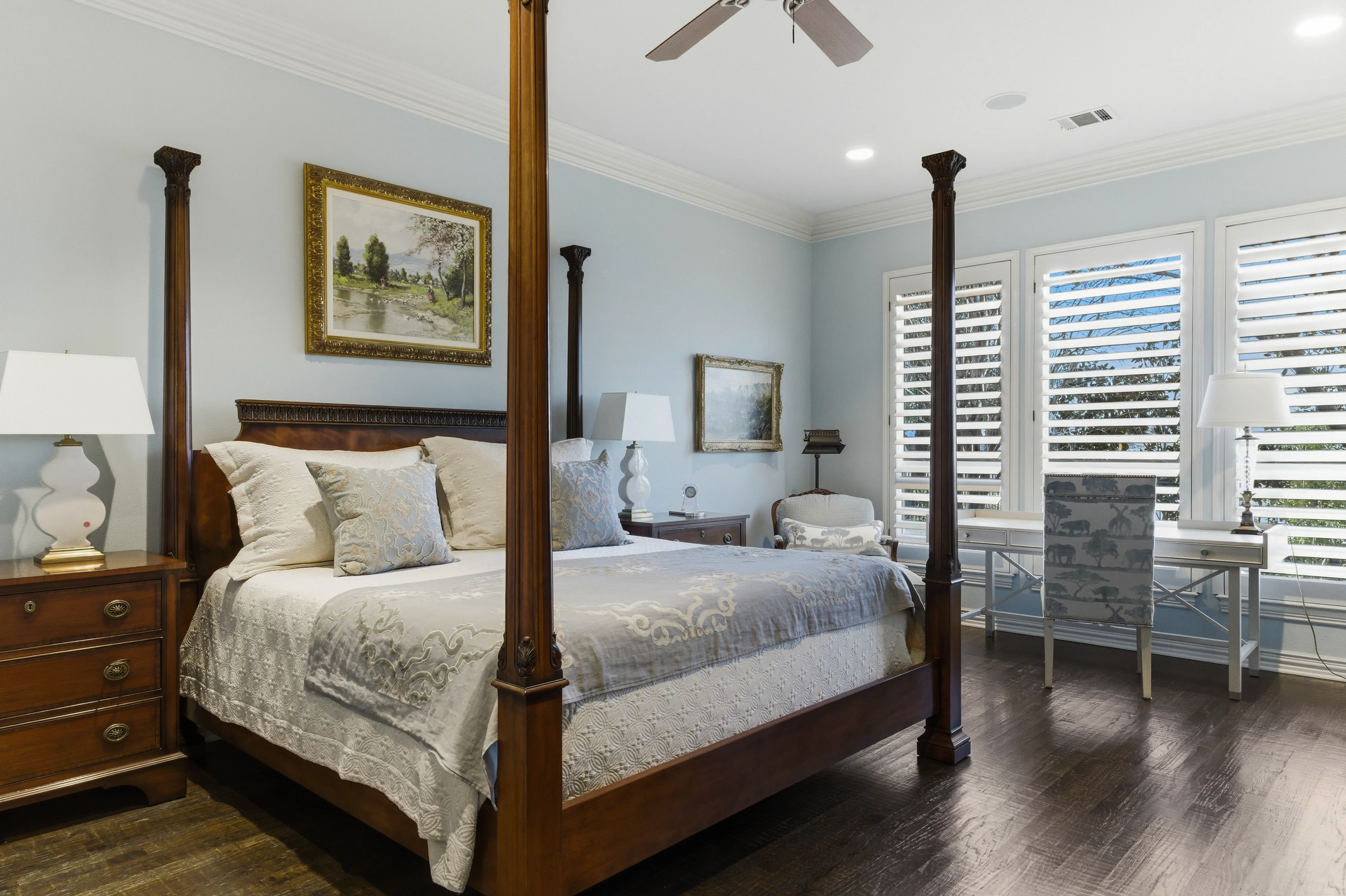 Spacious primary bedroom with four-poster bed and plantation shutters